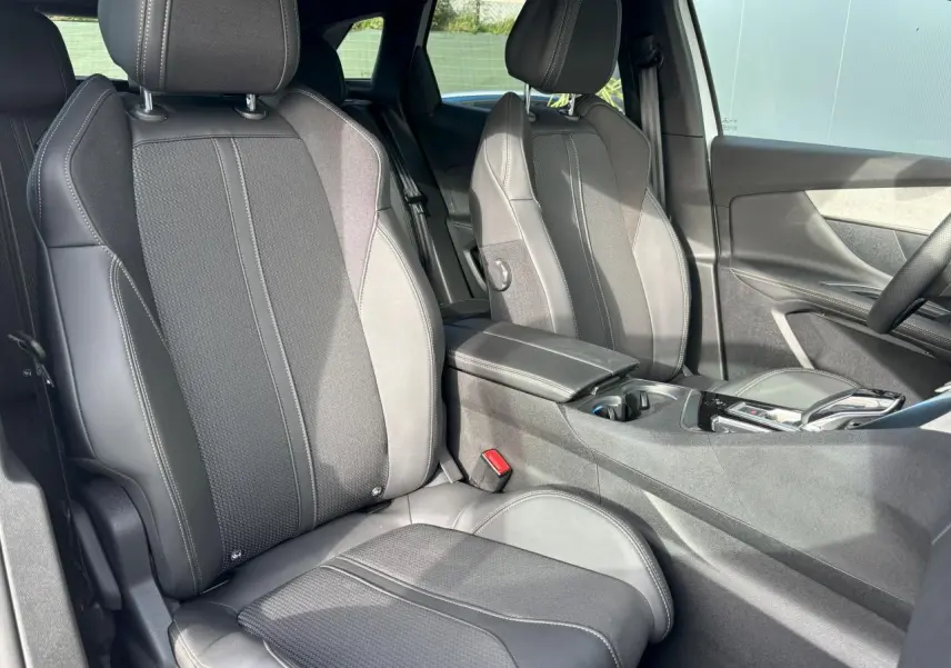 Vue intérieure sur les sièges avant en sellerie Mi-TEP/tissu gris foncé du Peugeot 3008 2024, avec accoudoir central.