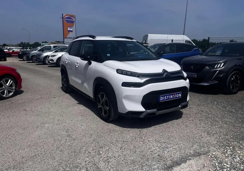 Citroën C3 Aircross blanc banquise vue 3/4 avant droit avec barres de toit noir brillant sur parking.