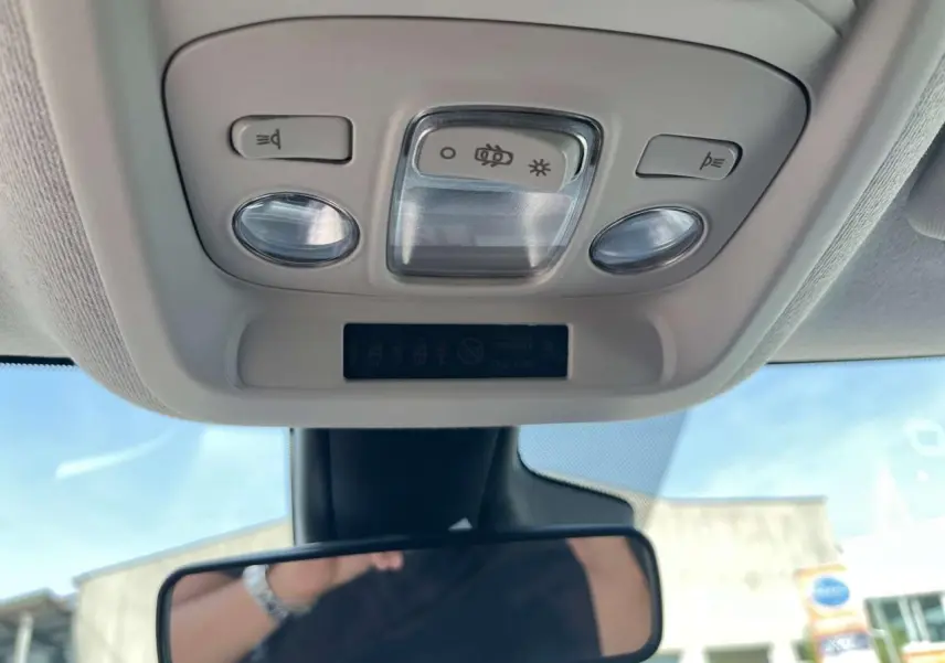 Vue intérieure en contre-plongée du plafonnier gris clair avec commandes d’éclairage et rétroviseur intérieur d’une Citroën C3 Aircross blanc banquise.