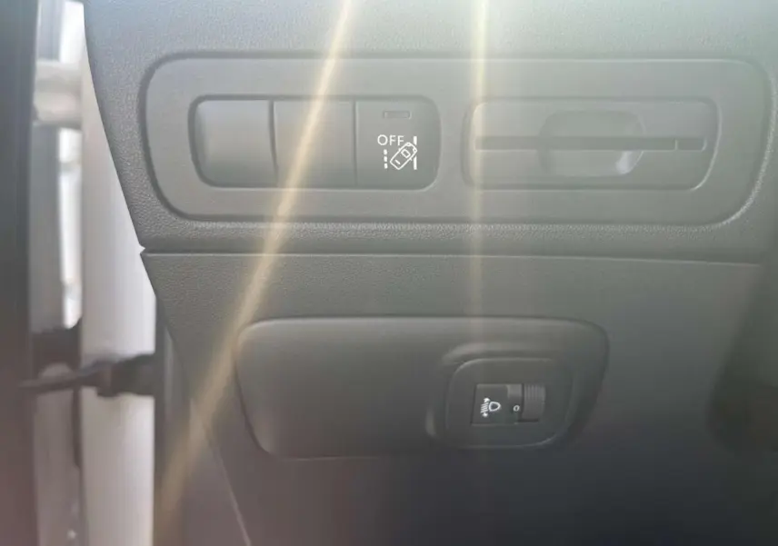 Détail des commandes d'assistance et réglage des phares dans l'habitacle d'une Citroën C3 Aircross blanc banquise.