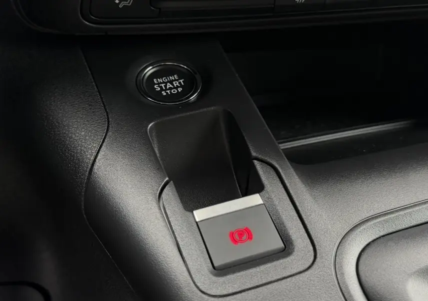 Gros plan sur la console centrale du Peugeot Rifter gris, avec bouton de démarrage et frein de stationnement électrique.