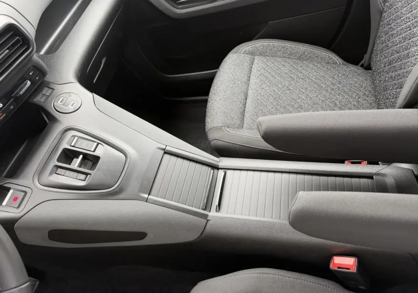 Vue intérieure centrée sur la console centrale et sièges avant gris du Peugeot Rifter 2026, version Allure.