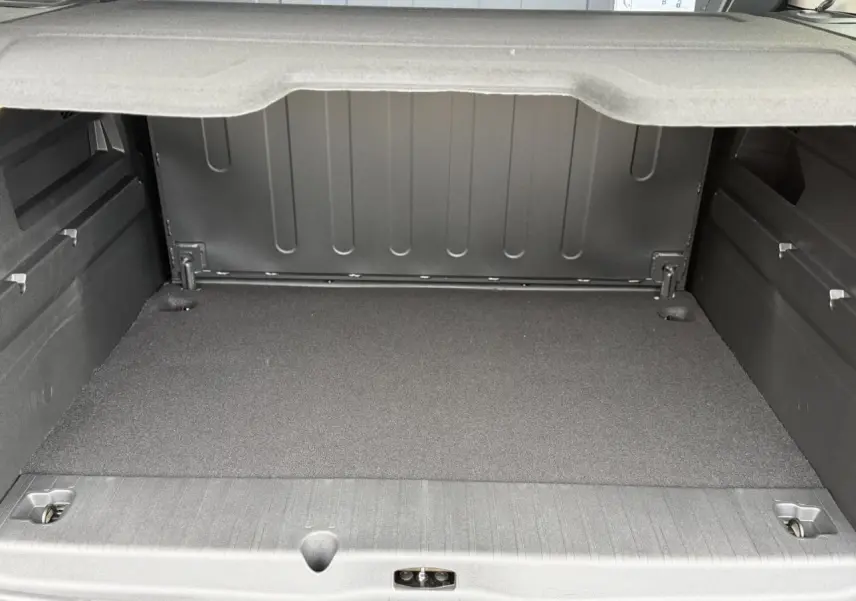 Coffre ouvert du Peugeot Rifter gris acier, vue arrière montrant l'espace de chargement et la tablette de séparation.