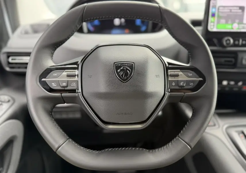 Vue rapprochée du volant cuir multifonction noir du Peugeot Rifter 2026 avec logo lion et commandes intégrées.