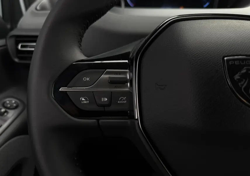 Gros plan sur le volant cuir multifonction du Peugeot Rifter 2026, avec commandes intégrées et logo lion central.