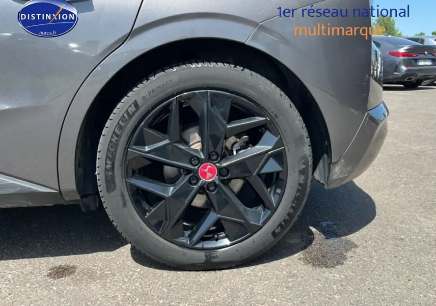 Gros plan sur la roue arrière droite noire avec jante design du DS4 gris platinium 2023 E-tense.