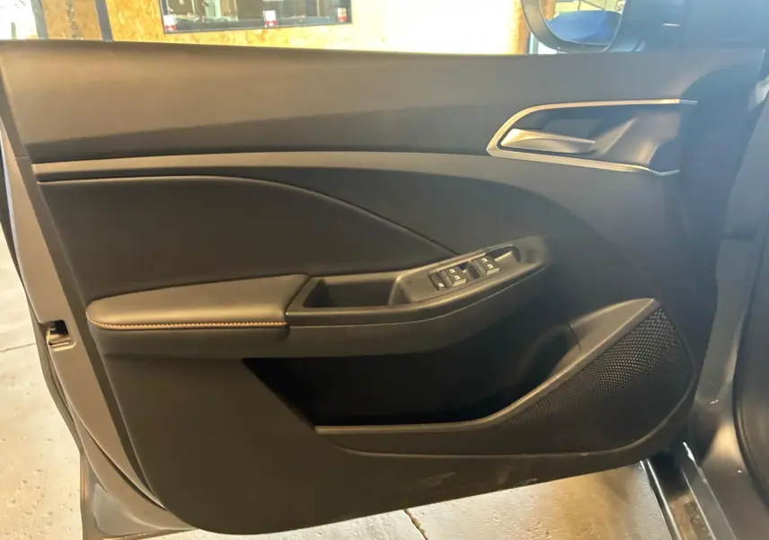 Vue intérieure de la porte avant gauche noire du MG3 1.5 HYBRID+ 195 LUXURY avec commandes de vitres et haut-parleur intégré.
