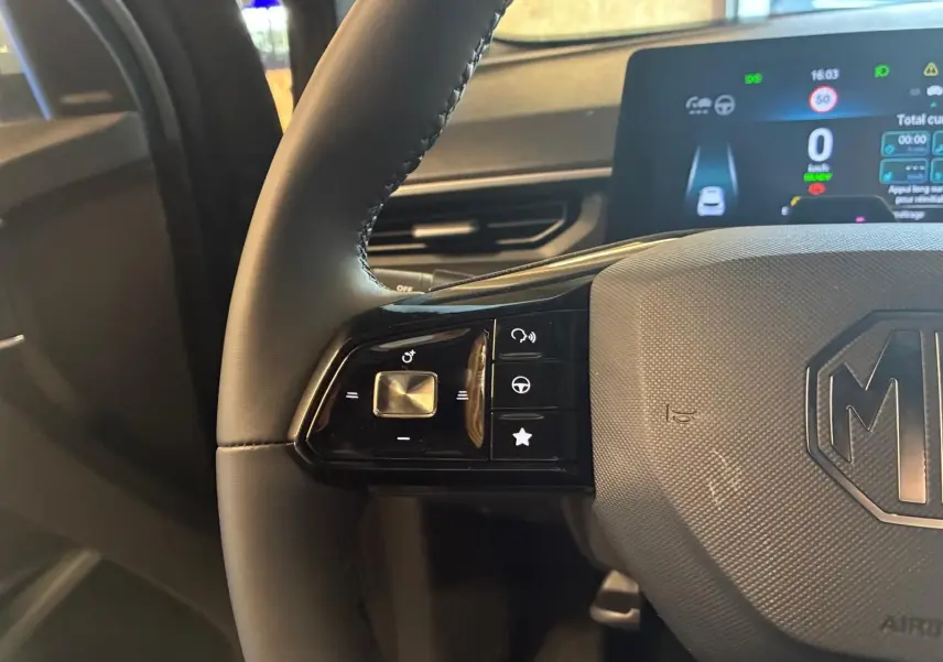 Gros plan sur le volant noir du MG3 1.5 HYBRID+ 195 LUXURY avec commandes intégrées et tableau de bord numérique visible.