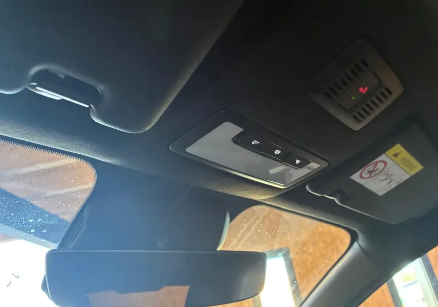 Vue intérieure du toit et du rétroviseur intérieur d'une MG3 1.5 HYBRID+ 195 LUXURY noire, avec commandes de plafonnier et pare-soleil visible.