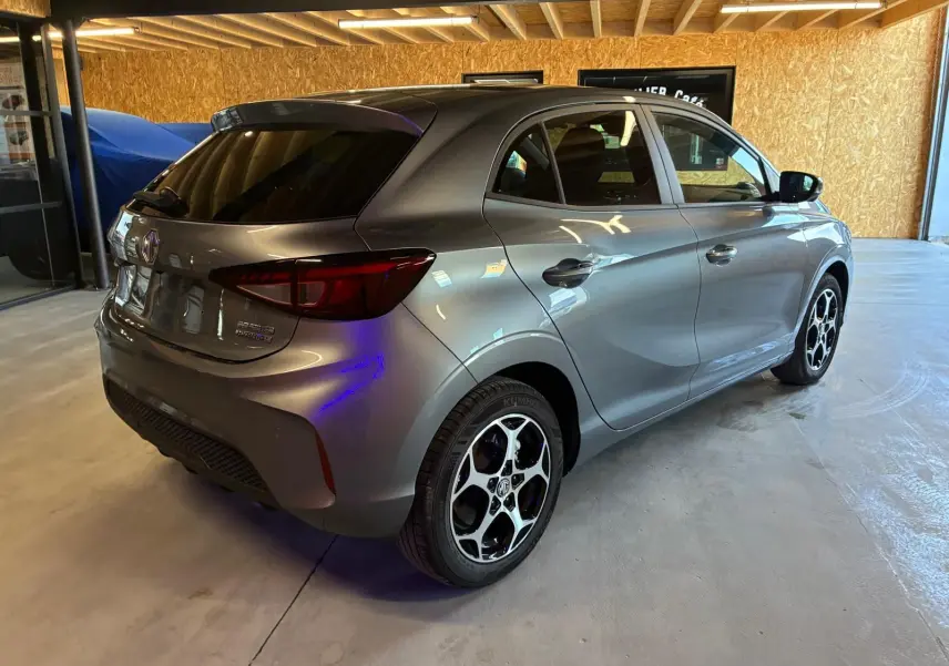 Vue 3/4 arrière droite d'une MG3 noire 2026 hybride, avec jantes alliage et vitres teintées dans un garage.