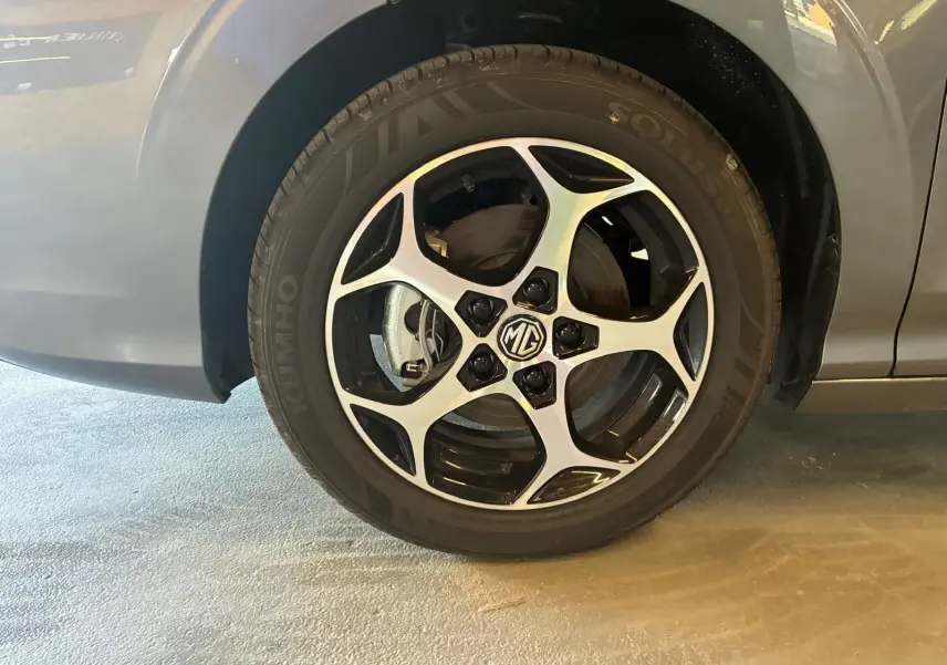 Gros plan sur la roue avant gauche noire d’une MG3 1.5 HYBRID+ 195 LUXURY avec jante alliage bicolore et logo MG central.