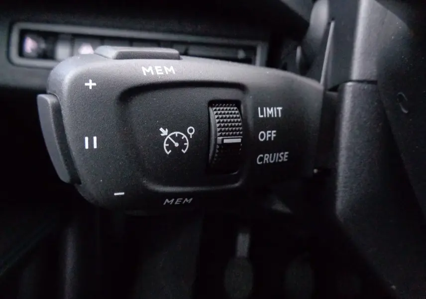 Gros plan sur la commande de régulateur de vitesse noire du Peugeot 3008 2023, version Essence, côté gauche du volant.