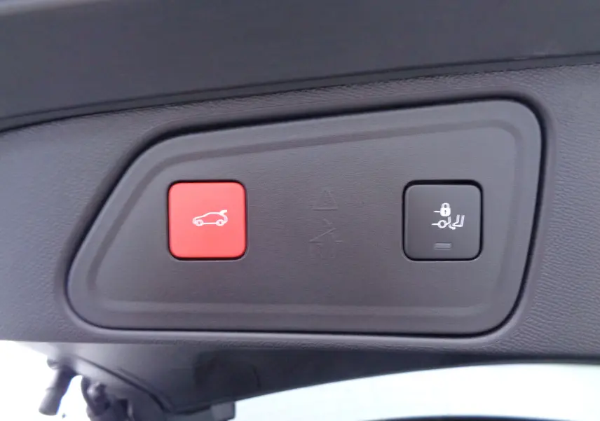 Boutons de commande du hayon et verrouillage des sièges arrière sur le coffre d'un Peugeot 3008 noir Perla Nera 2023.