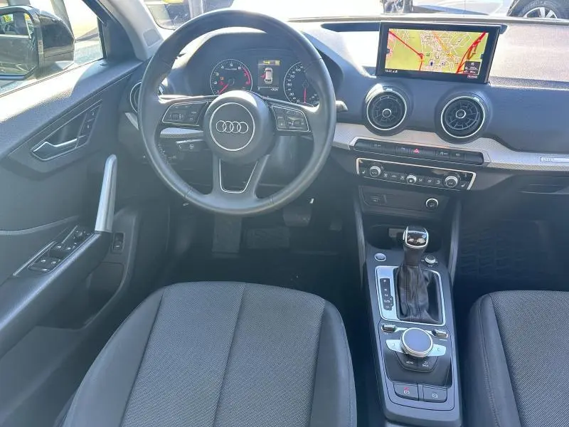 Vue intérieure avant de l'Audi Q2 35 TFSI S line 2023, tableau de bord avec écran navigation et volant multifonction.