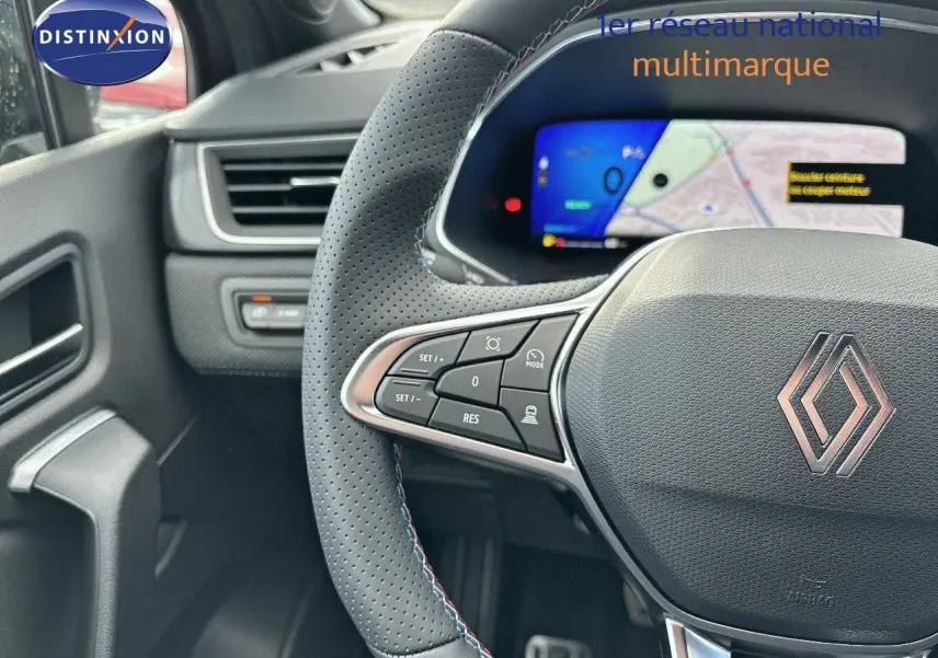 Vue rapprochée du volant noir perforé avec commandes intégrées et tableau de bord numérique du Renault Symbioz hybride.