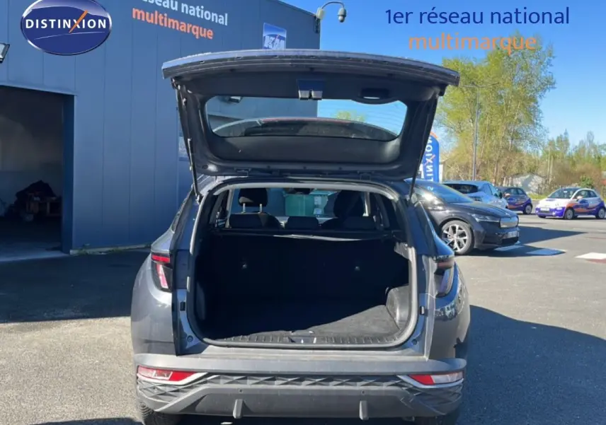 Vue arrière d’un Hyundai Tucson gris foncé métal 2021 avec coffre ouvert, dévoilant l’espace de chargement vide.