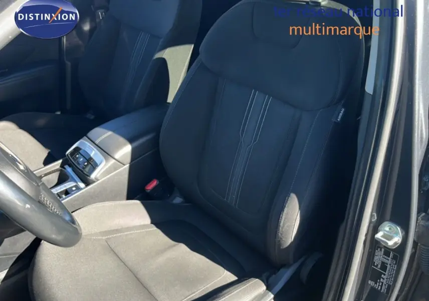 Vue intérieure côté conducteur du Hyundai Tucson gris foncé métal, mettant en valeur le siège avant en tissu noir et la console centrale.