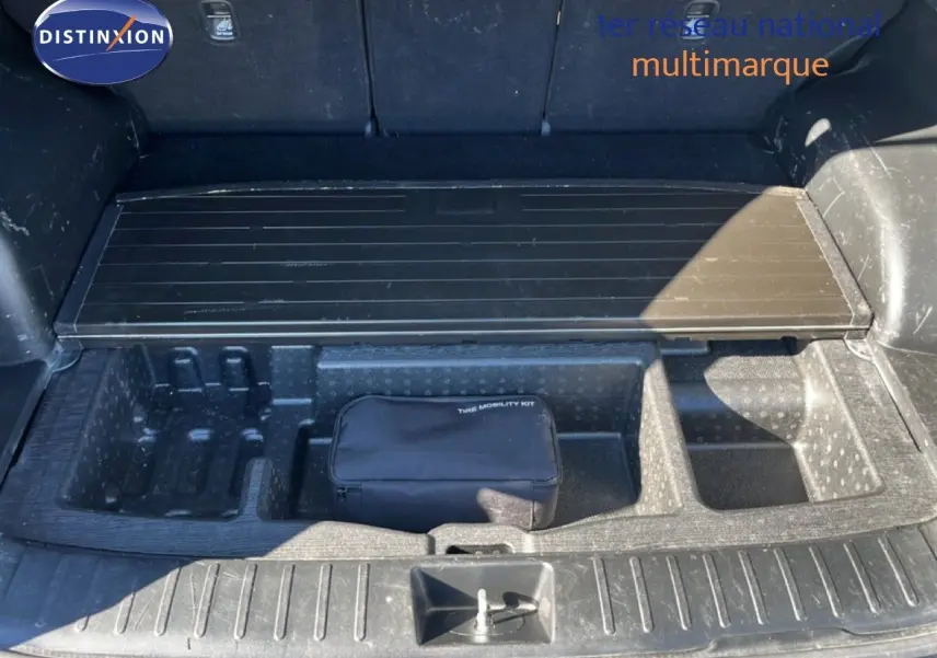 Coffre ouvert du Hyundai Tucson gris foncé, montrant le rangement sous plancher avec trousse de mobilité.
