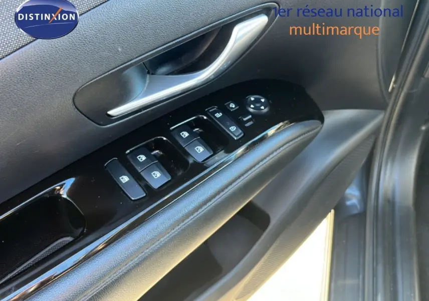 Gros plan sur la porte côté conducteur du Hyundai Tucson gris foncé, montrant les commandes des vitres et la poignée intérieure.