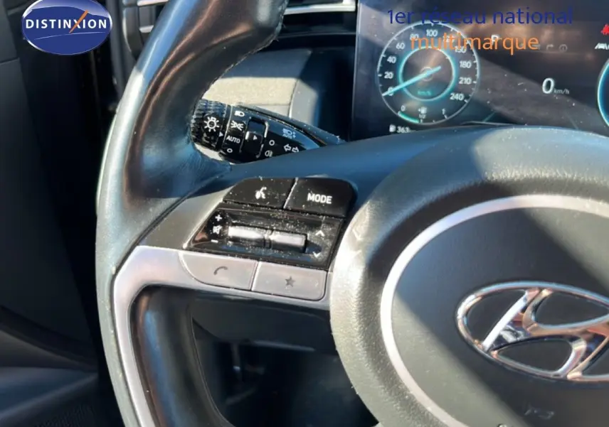 Gros plan sur le volant et le tableau de bord du Hyundai Tucson gris foncé 2021, avec commandes intégrées et affichage digital.