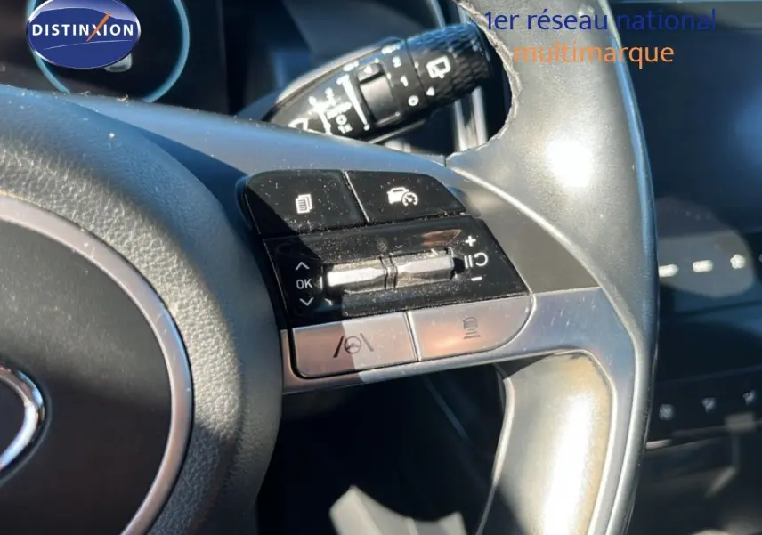 Gros plan sur les commandes au volant gris foncé du Hyundai Tucson 2021, mettant en valeur les boutons multifonctions.