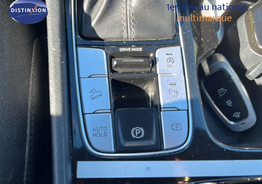 Gros plan sur la console centrale du Hyundai Tucson gris foncé, montrant les commandes de conduite et la clé.