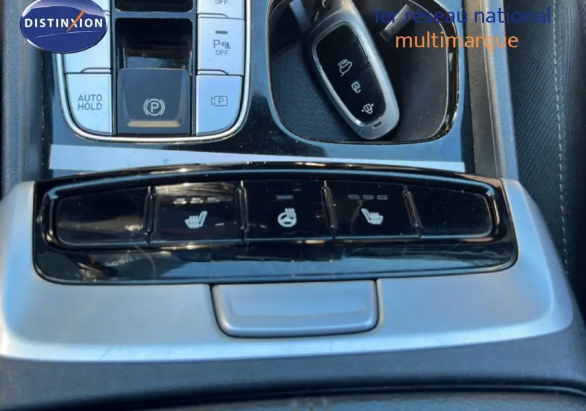 Vue rapprochée de la console centrale du Hyundai Tucson 2021, boutons de sièges chauffants et clé noire visible.