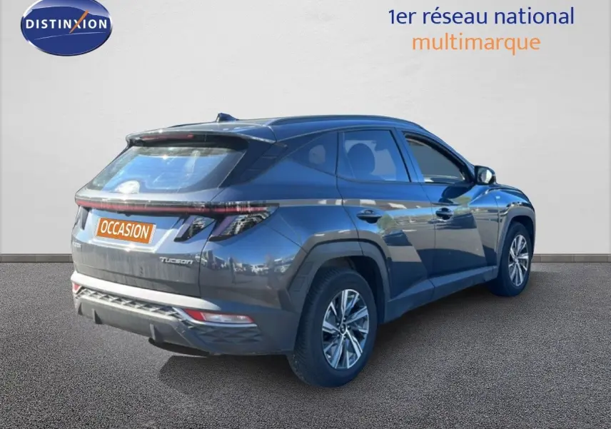 Vue 3/4 arrière droite d'un Hyundai Tucson gris foncé métal 2021 avec feux arrière étirés et jantes alliage.