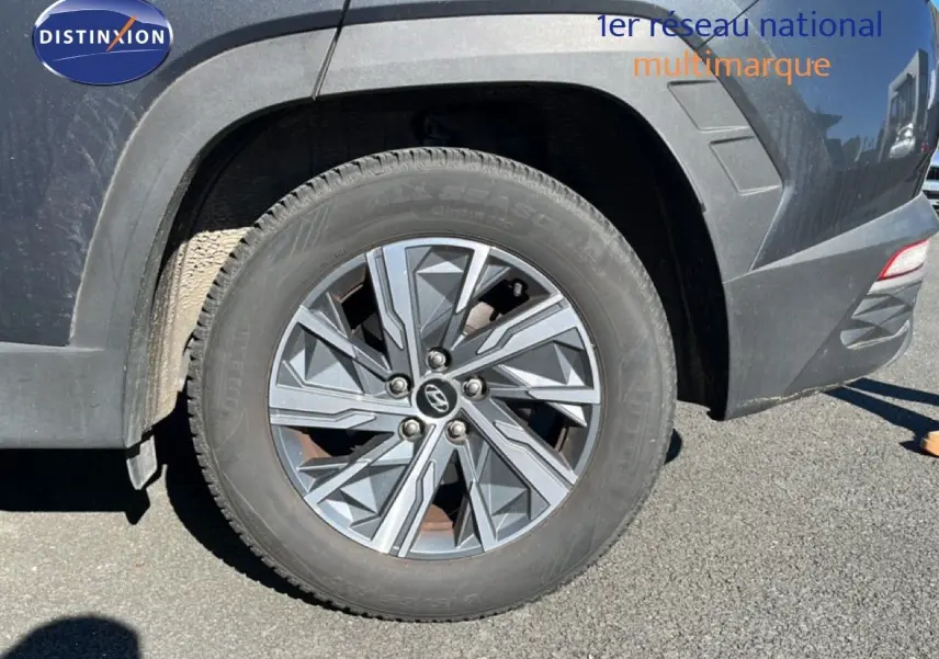 Gros plan sur la roue arrière droite d’un Hyundai Tucson gris foncé métal avec jante alliage au design géométrique.