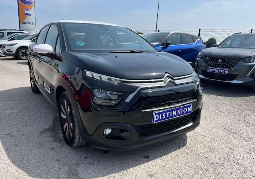 Citroën C3 2023 noir avec toit blanc en 3/4 avant droit, jantes alliage et rétroviseurs blancs visibles.