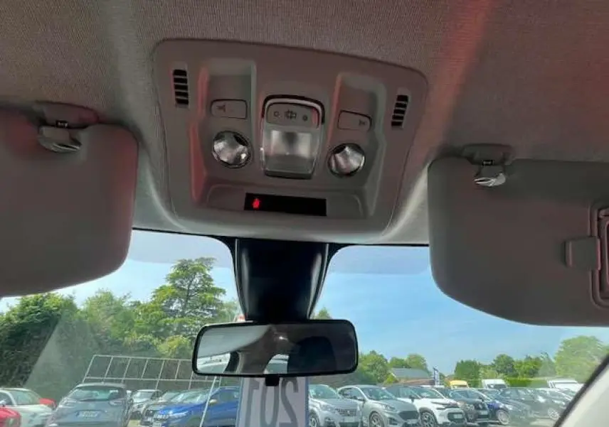 Vue intérieure du toit et rétroviseur central d'une Citroën C3 2023, avec pare-soleil baissé et ciel visible à travers le pare-brise.