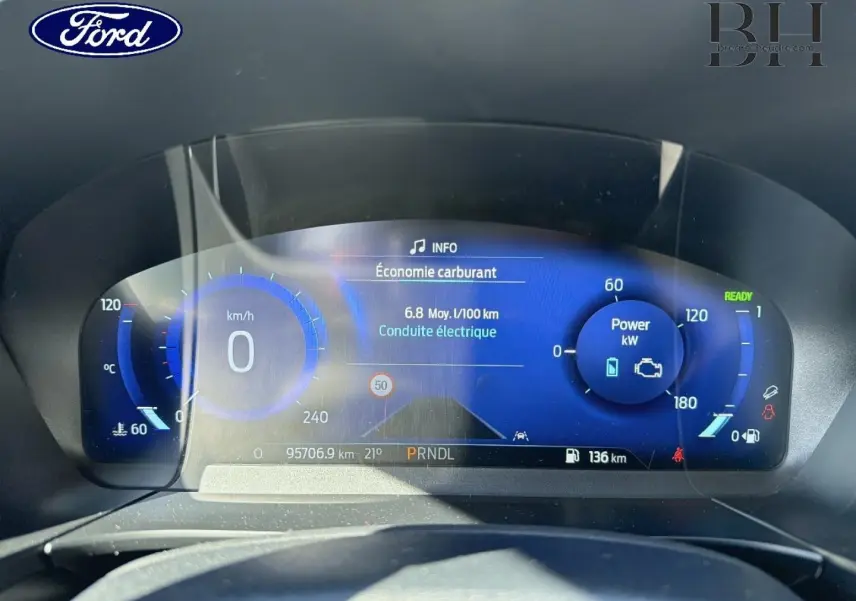 Vue rapprochée du tableau de bord numérique bleu du Ford Kuga 2021 affichant consommation et puissance électrique.