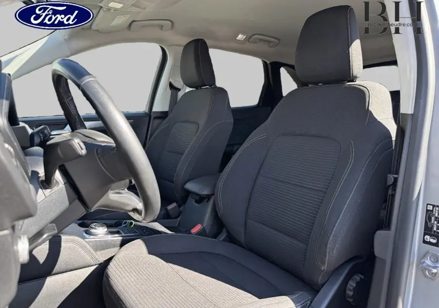 Vue intérieure côté conducteur du Ford Kuga 2.5 Duratec gris Solar, sièges tissu noir avec volant cuir multifonction.