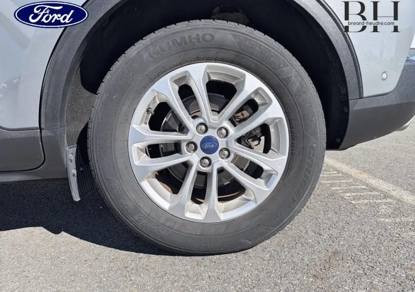 Gros plan sur la roue avant gauche du Ford Kuga gris Solar Métallisé, mettant en valeur la jante alu et le logo Ford central.