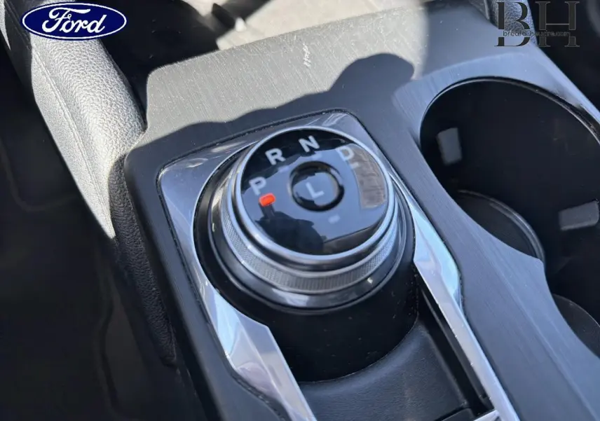 Gros plan sur la molette de sélection de vitesses du Ford Kuga 2.5 Hybride, finition Titanium, avec console noire et détails chromés.