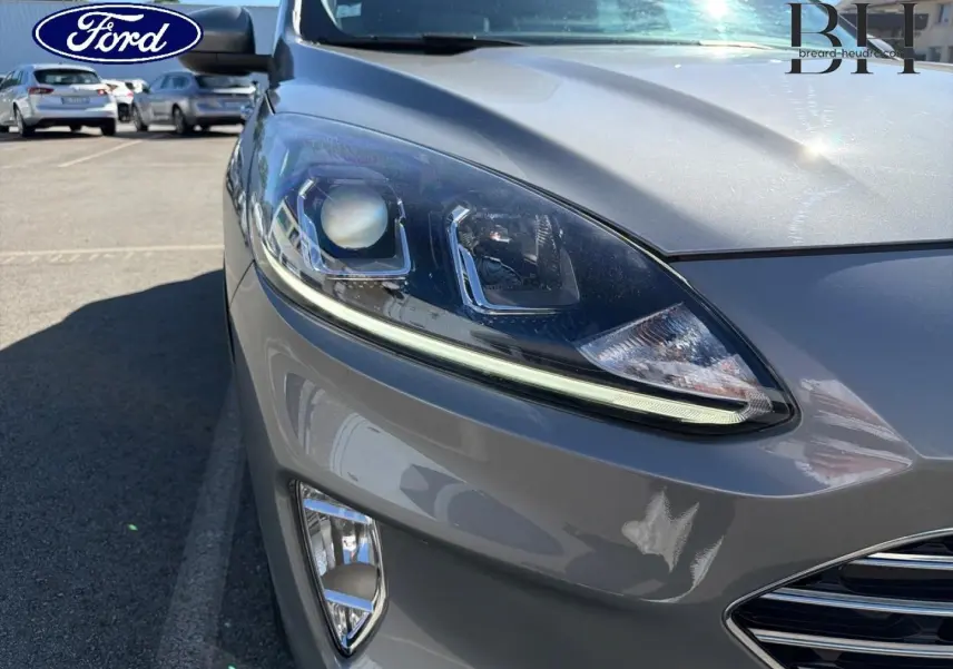 Gros plan sur l'avant droit du Ford Kuga gris Solar métallisé, mettant en valeur le phare LED et la calandre chromée.