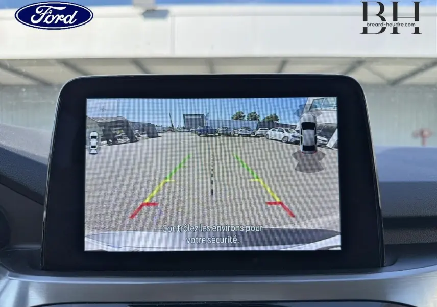 Écran tactile intérieur montrant la caméra de recul avec lignes de guidage colorées sur un Ford Kuga gris Solar.