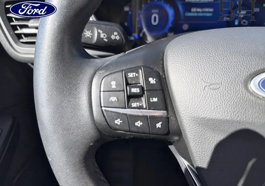 Gros plan sur le volant cuir multifonction noir du Ford Kuga 2021, avec commandes de régulateur de vitesse et audio.