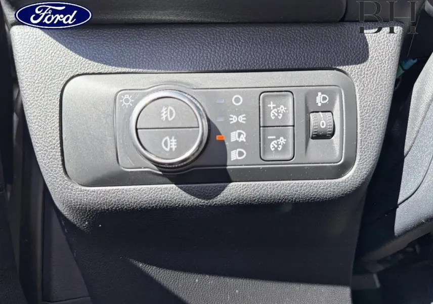 Gros plan sur les commandes d’éclairage intérieures du Ford Kuga 2021, avec molette et boutons noirs sur tableau de bord gris.