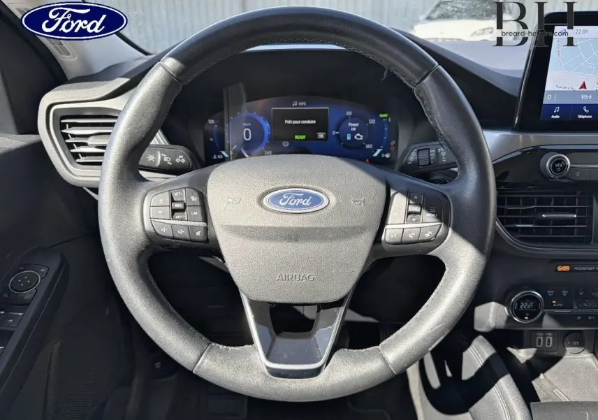 Vue intérieure centrée sur le volant cuir multifonction noir du Ford Kuga 2021 avec tableau de bord digital et écran tactile.