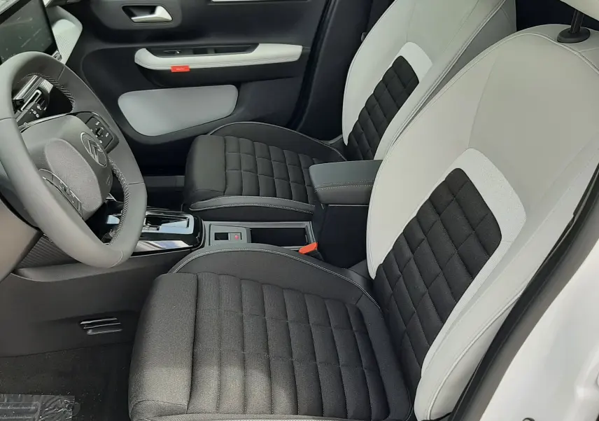 Vue intérieure côté conducteur de la Citroën C3 Aircross 2026, sièges bicolores noir et blanc avec tissu matelassé.
