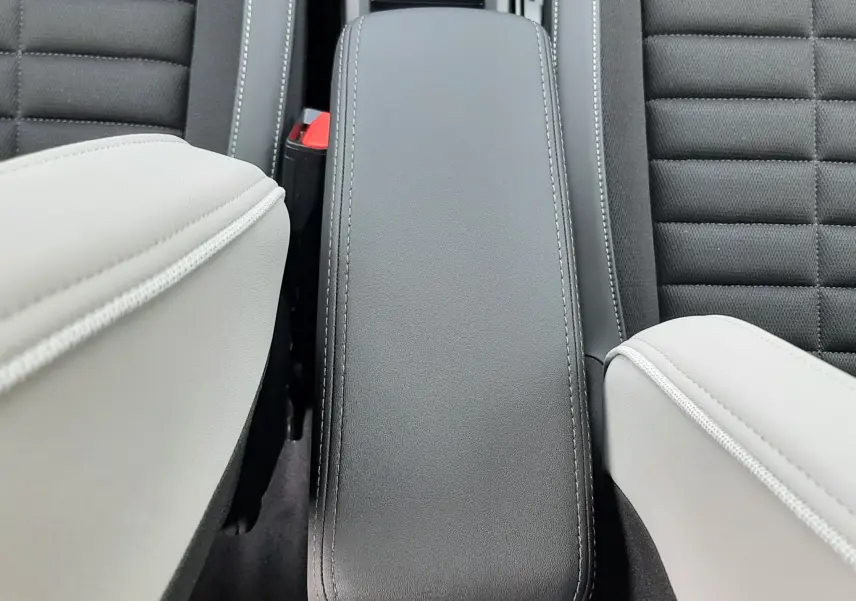 Vue plongeante sur l'accoudoir central noir entre les sièges avant bicolores noir et blanc du Citroën C3 Aircross 2026.
