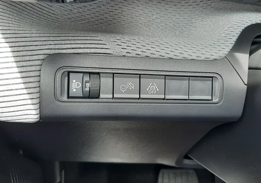 Vue rapprochée des commandes de réglage des phares et aides à la conduite sur le tableau de bord d'une Citroën C3 Aircross 2026.