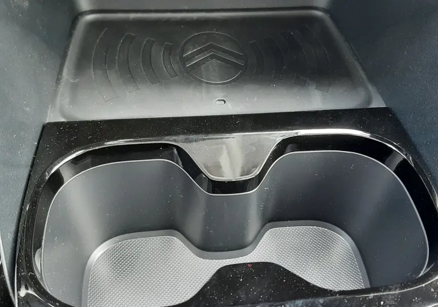 Gros plan sur le porte-gobelets noir brillant et la zone de recharge sans fil avec logo Citroën dans une Citroën C3 Aircross 2026.