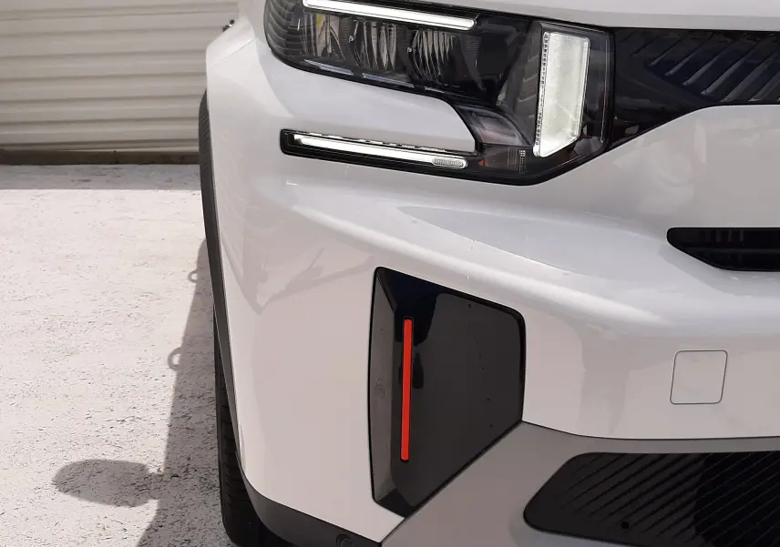 Gros plan sur l'avant gauche blanc banquise du Citroën C3 Aircross 2026 avec phare LED et détails noirs contrastants.