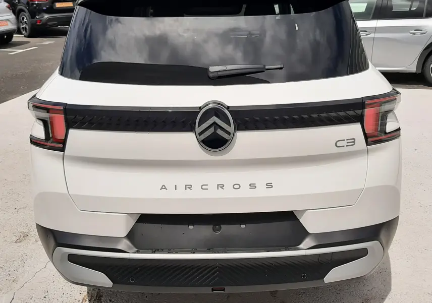 Vue arrière d'un Citroën C3 Aircross blanc banquise avec toit noir, feux arrière LED et logo central chromé.