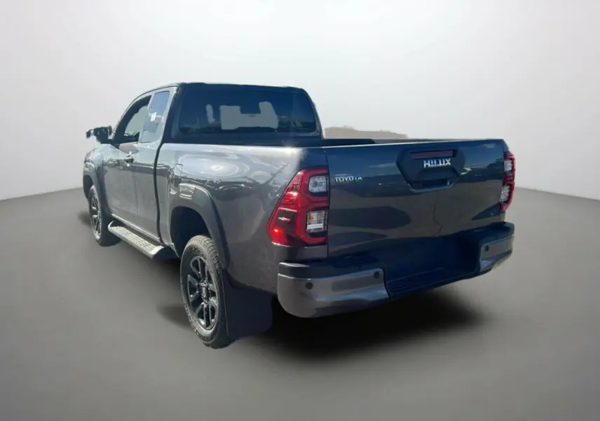 Toyota Hilux 4x4 gris atlas vue 3/4 arrière droit, avec benne ouverte et jantes noires distinctives.