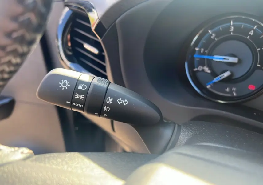 Gros plan sur la commande des phares et clignotants à gauche du volant du Toyota Hilux Invincible gris atlas 2025.