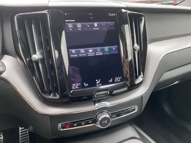 Tableau de bord du Volvo XC60 noir 2021, avec écran tactile central et commandes de climatisation visibles.