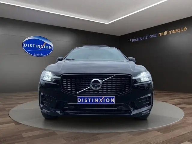Vue frontale d'un Volvo XC60 noir avec calandre R-Design et phares LED allumés dans un showroom.